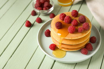Plate of tasty pancakes with honey and berries on color wooden background