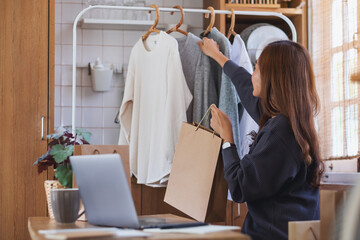 A female entrepreneur using laptop computer for selling clothes online or review product on social media at home