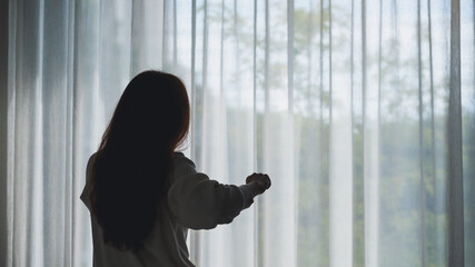 Rear view image of a woman do stretching after waking up in bedroom