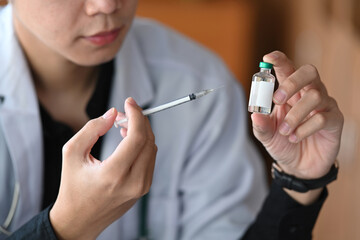 Cropped shot doctor holding syringe and vaccine bottle. Medicine and healthcare concept.