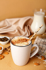 Cup of tasty almond latte with cinnamon on color background