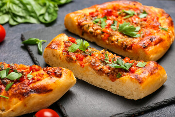 Board with sliced Turkish Pizza on black background
