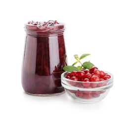 Glass jar of tasty cranberry jam and bowl with berries on white background