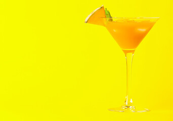 Glass of cold melon cocktail on yellow background