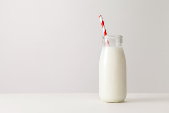 A glass of milk with drinking straw on white background. - Powered by Adobe