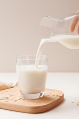 milk pouring from glass milk pot into a glass on table.