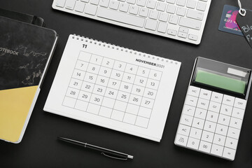 Calendar page of November 2022, computer keyboard, notebook and calculator on dark background. Black Friday