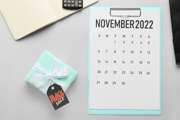 Calendar page of November 2022 and gift on grey background. Black Friday