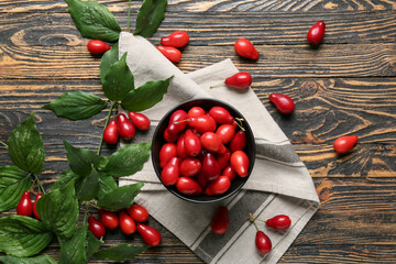 Branch and bowl with fresh dogwood berries on wooden background