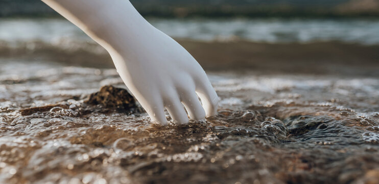 Robot with hand in water at lakeshore