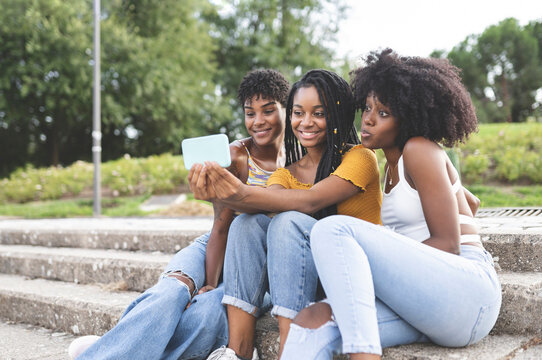Happy female friends taking selfie on smart phone in park