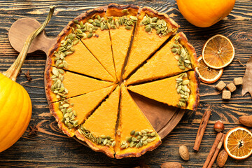 Board with delicious pumpkin pie on wooden background