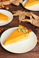 Plate with piece of delicious pumpkin pie on wooden background
