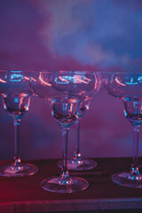 empty martini glasses in a subdued warm light against the background of a wall painted to match the sky around the smoke, party invitation template with free space for text