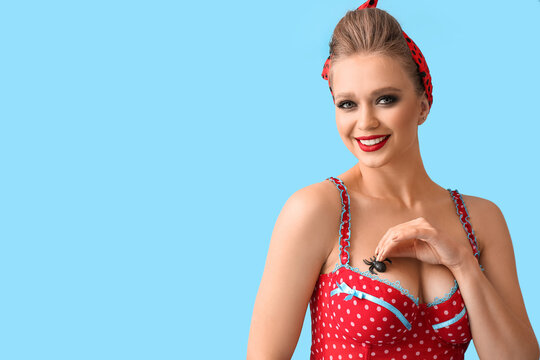 Sexy young woman with spider on her bust against color background