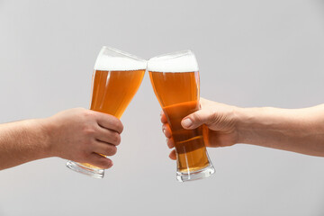 Hands with glasses of beer on grey background