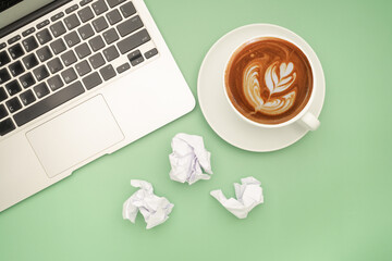 Working desk table concept. Top view of a laptop, crumpled paper, and a white coffee cup isolated...