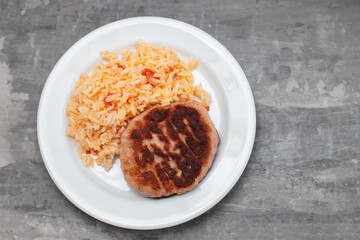 fried meat with rice and tomato on white dish