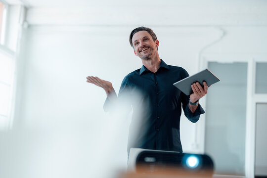 Smiling businessman with digital tablet during presentation in board room