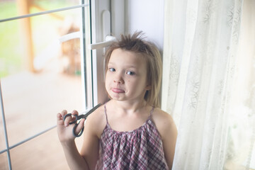 Cute funny caucasian girl child with scissors cuts her hair, hooliganism and pranks child, child...