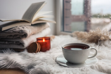 Beautiful autumn composition with burning candle and cup of tea on window sill