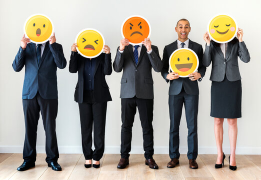 Business people standing and holding emoji icons