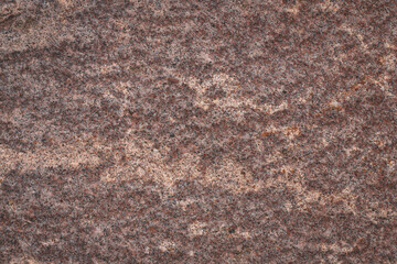 Red granite texture. A variegated, spotted background of red (brown) granite. The stone granite surface of brown-gray color. Surface view of granular igneous rock