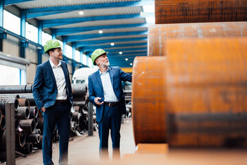 Male inspectors with hardhat checking rusty pipe in warehouse