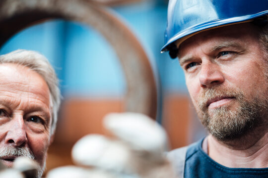 Male warehouse worker checking equipment with manager in industry
