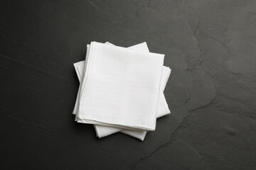 White handkerchiefs folded on black table, top view