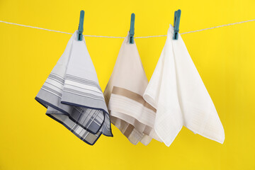 Many different handkerchiefs hanging on rope against yellow background