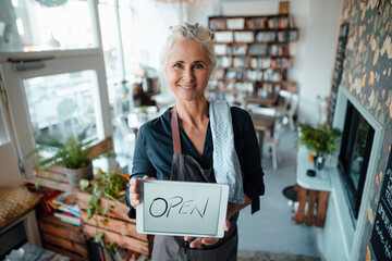 Female entrepreneur holding digital tablet with open text in coffee shop