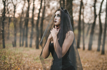Brunette witch girl conjures in the forest conducts rituals with a fantasy skull nature magic in...