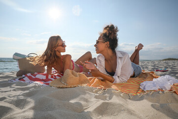 Friends lying on beach towels near sea
