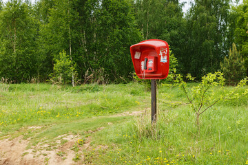 red payphone. Payphone standing in the field. Village telephone. Russia