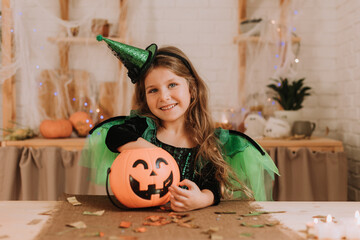portrait of a cheerful little girl in a Halloween costume with a pumpkin and burning candles. autumn concept. space for text. High quality photo