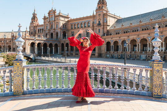 Female flamenco artist dancing with hands raised at Plaza De Espana in Seville, Spain on sunny day