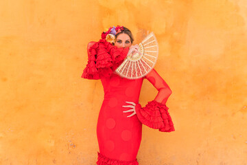Female dancer wearing red traditional dress standing in front of orange wall