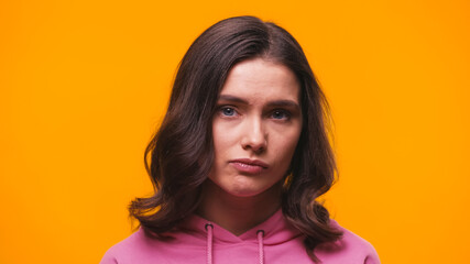 Fototapeta premium offended woman in pink hoodie looking at camera isolated on yellow