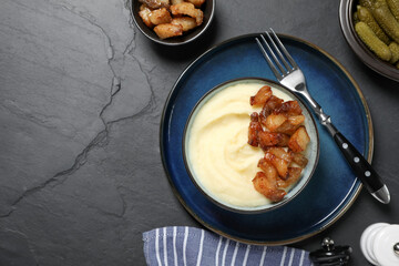 Potato puree and tasty fried cracklings served on black table, flat lay with space for text. Cooked...