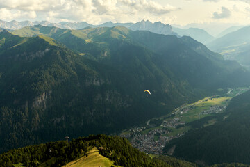 Gleitschirm Flieger über einen satt grüner Tal in den italienischen Dolomiten, Südtirol