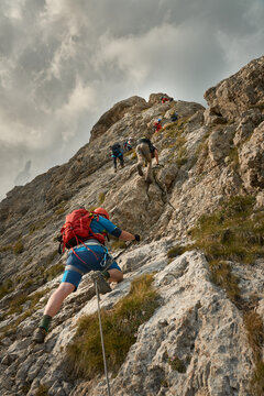 mixed gender group of climbers heading up a steep rock face the via ferrata Rodella near Sella Pass in South Tyrol, Dolomites, Italy