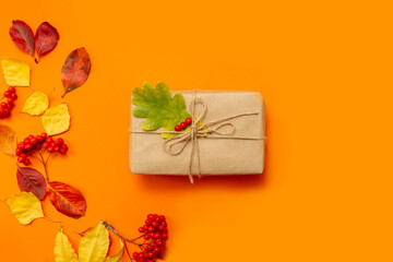 Autumn composition. Gift box, dried leaves on an orange background. Autumn, fall concept. Flat lay, top view, copy space