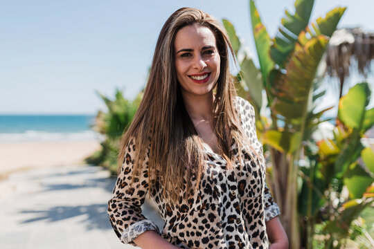 Smiling woman wearing Cheetah print shirt at beach on sunny day