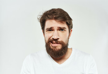 Obraz premium bearded man in a white t-shirt irritated facial expression Studio
