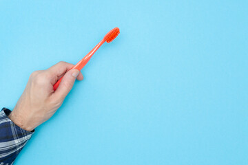 Man holds a toothbrush on a blue background. Copy space. Place for your text. Hygiene of teeth and oral cavity. Mockup. Dental care. Isolated.