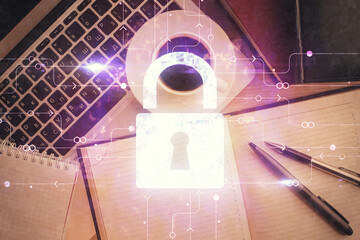 Double exposure of lock hologram drawing over study table background with computer. Concept of data security. Top view.