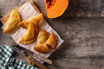 Pumpkin empanadillas on wooden table. Top view. Copy space
