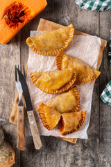 Pumpkin empanadillas on wooden table.	