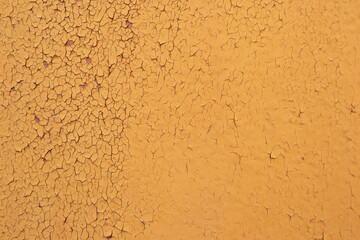 A peeling layer of orange paint on the wall. Background with peeling orange paint